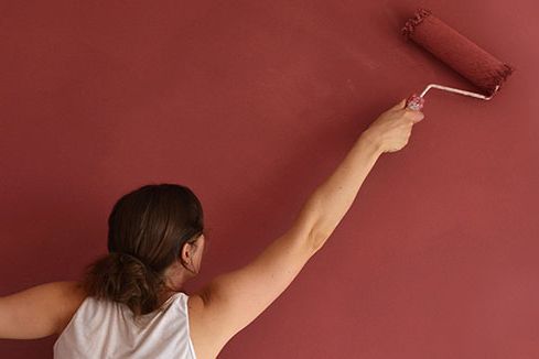 Frau streicht eine Wand mit einem Farbroller